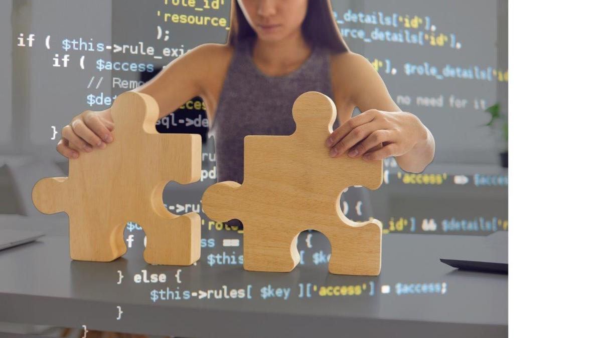 Woman assembling large wooden puzzle pieces with computer code overlay.